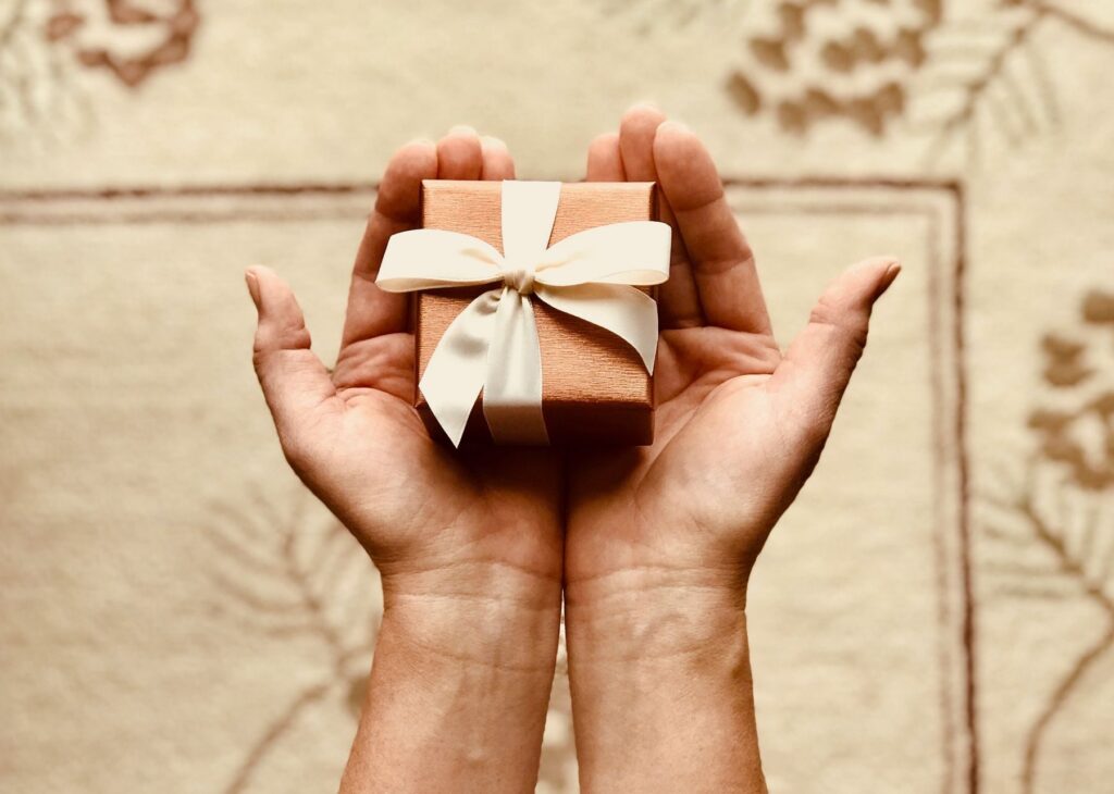 Two hands holding a small wrapped gift box